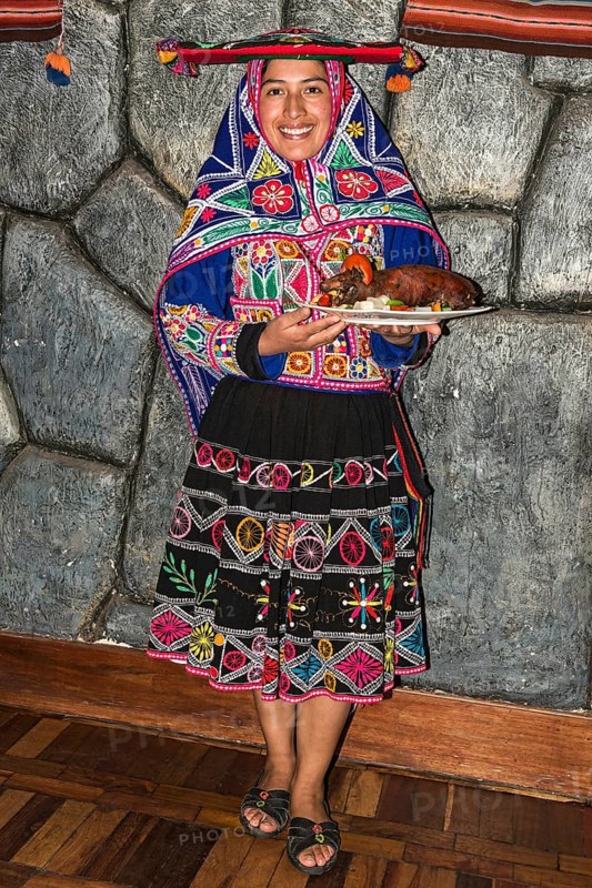 Woman serving roasted guinea pig Cuy chactado