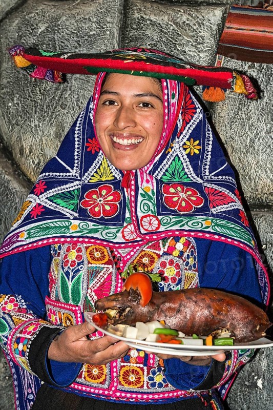 Woman serving roasted guinea pig Cuy chactado