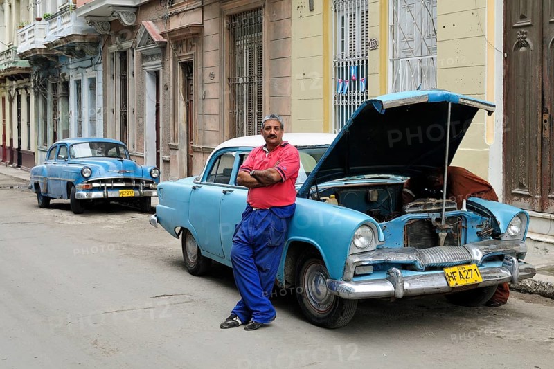 Man next to American classic car being repaired in the streets