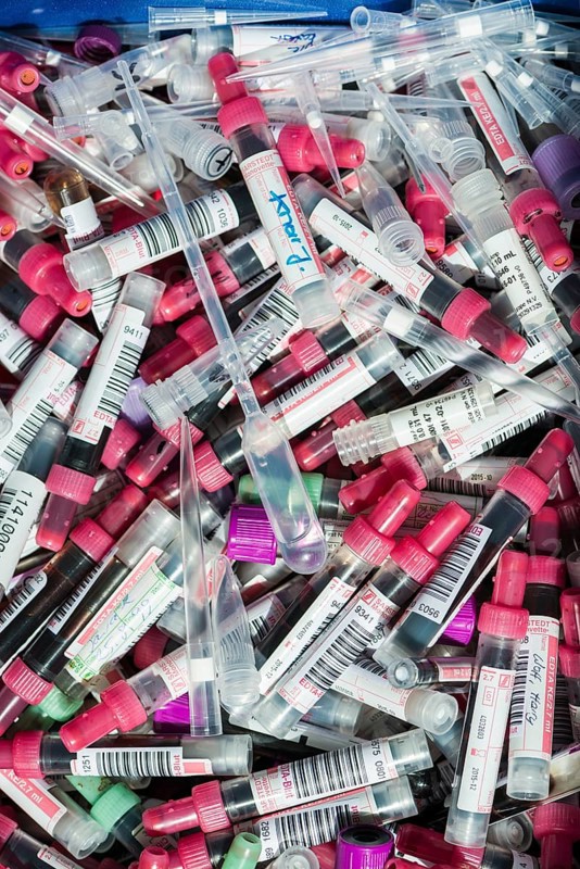 Transparent monovettes containing different blood samples in a garbage bin
