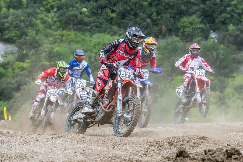 Group of motorcyclists on motocross bikes riding on a dirt track
