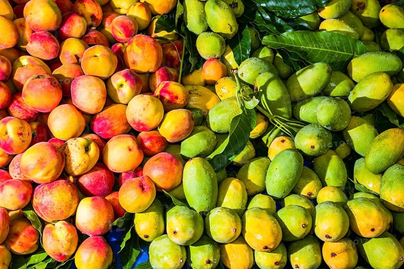 Fresh mangoes and peaches are arranged for sale in the fruit market