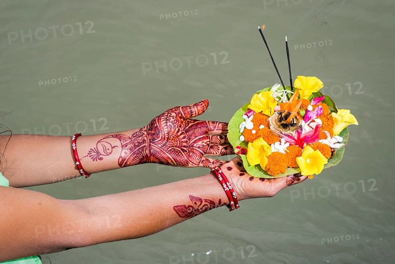 A pair of henna painted hands are holding a deepak