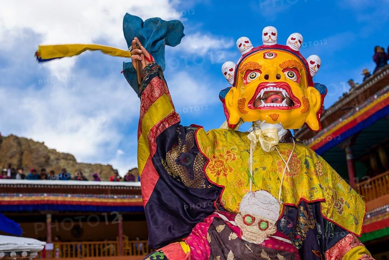 Monks with big wooden masks and colorful costumes are performing ritual dances at Hemis Festival in the courtyard of the monastery