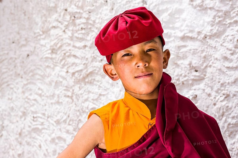 A portrait of a young monk of the Kagyu lineage of Buddhism in red clothes