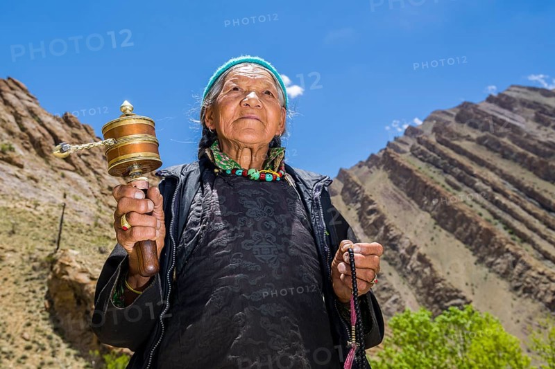 An old Ladakhi woman is turning a prayer wheel