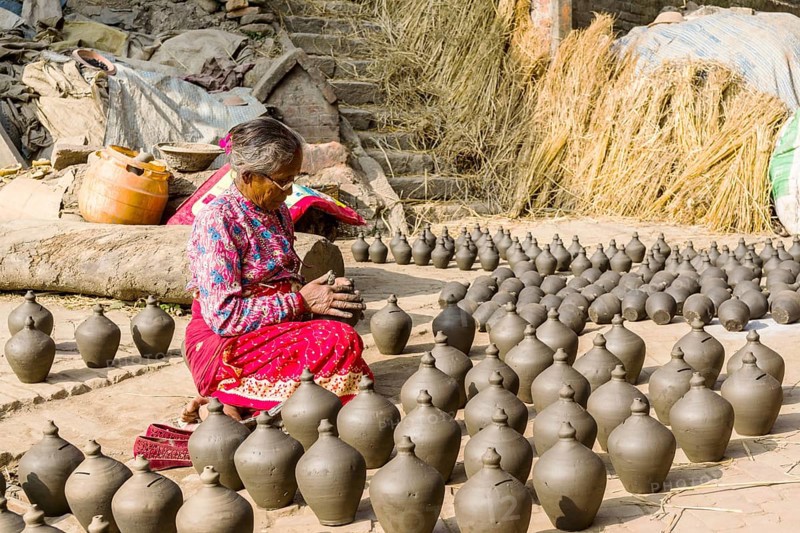 A woman is working at pottery in the streets