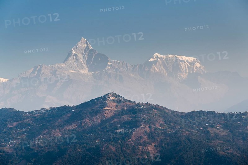 Summits of Annapurna III and Machapuchare in the haze behind the Sarangkot mountain ridge