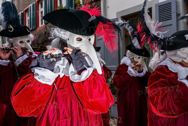 Many different groups of masked people walking through the streets of Basel