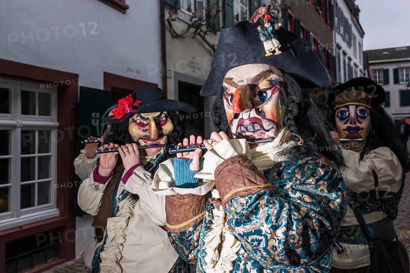 Many different groups of masked people walking through the streets of Basel