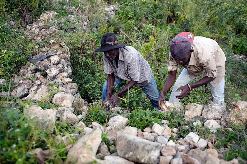 Men building walls with boulders to prevent erosion on deforested slopes
