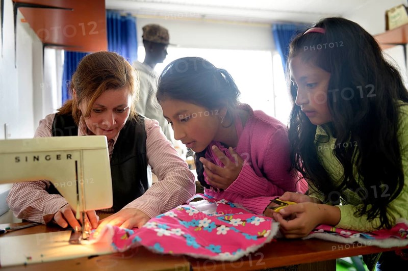 Girls and teacher using sewing machine