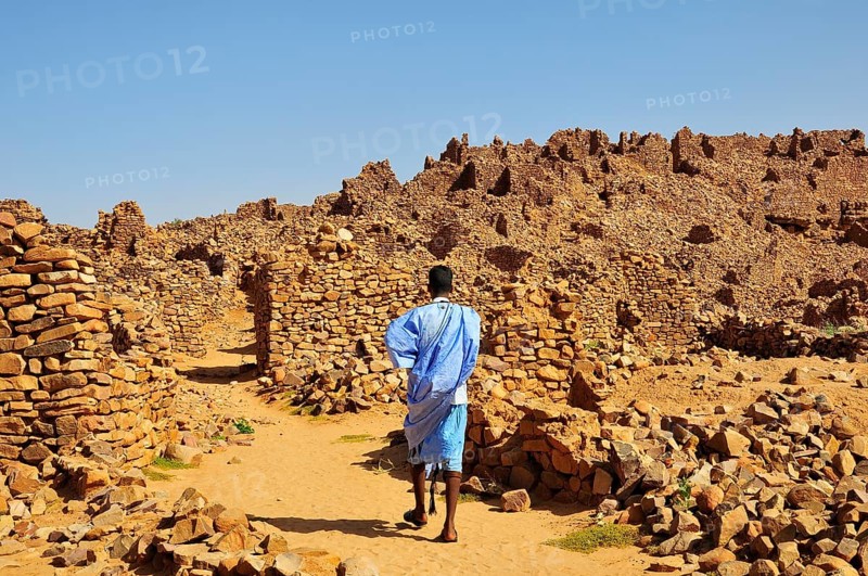 Man in blue boubou among the ruins of the fortified trading post or Ksar