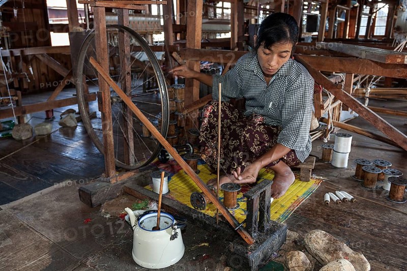 Local woman weaving threads from the stems of the lotus plant