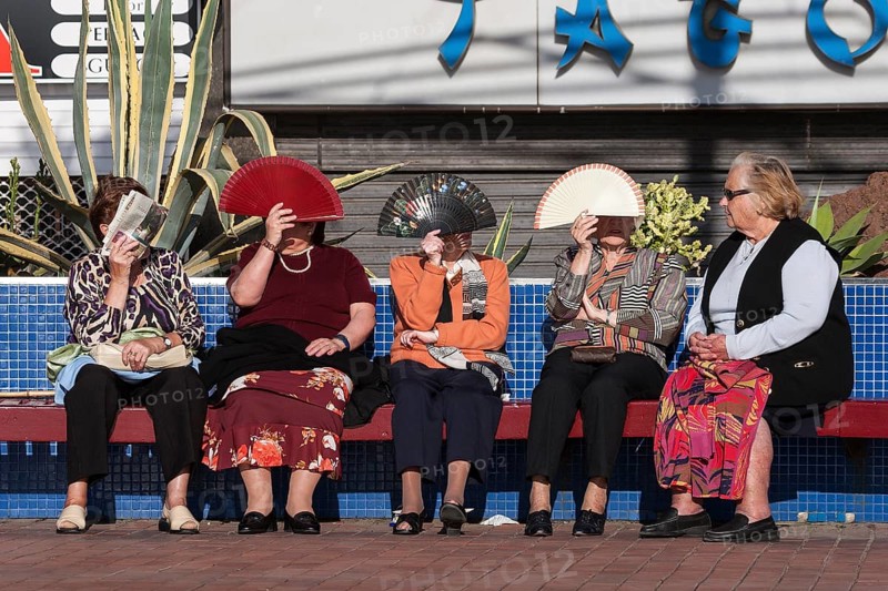Women protecting their faces from the sun with fans
