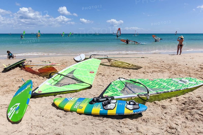 Windsurfing boards and sails lying on the beach