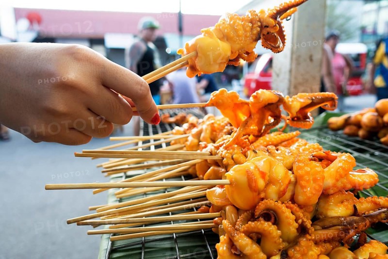 Hand holding a skewer with octopus