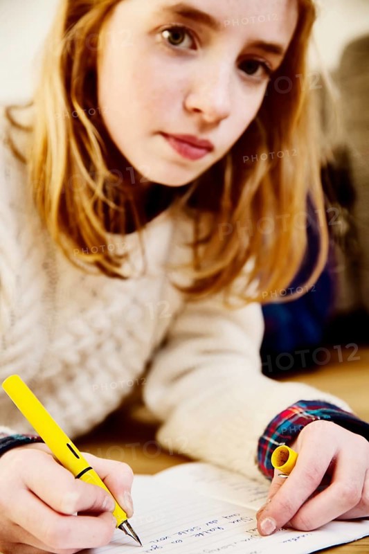 Girl doing her homework on the floor at home