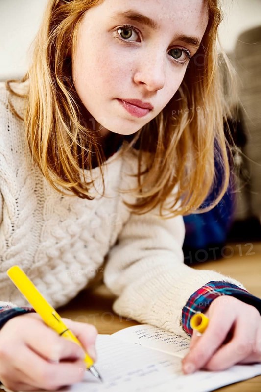 Girl doing her homework on the floor at home