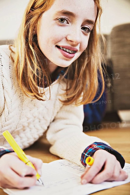 Girl doing her homework on the floor at home