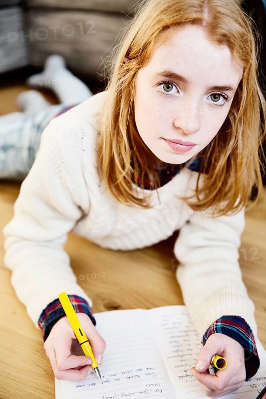 Girl doing her homework on the floor at home