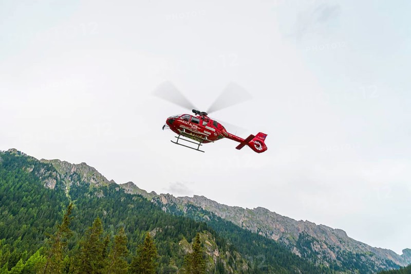 Red Aiut Alpin rescue helicopter I-AIUT taking off from meadow