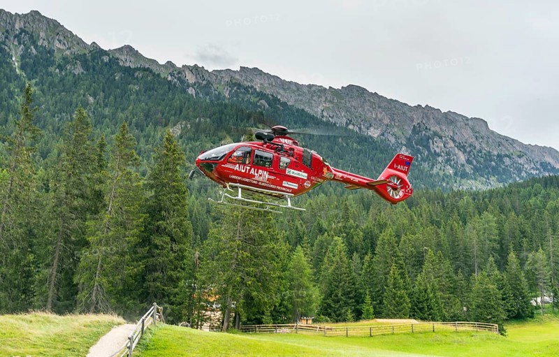 Red Aiut Alpin rescue helicopter I-AIUT taking off from meadow