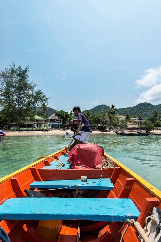 Local man steering longtail boat from rear