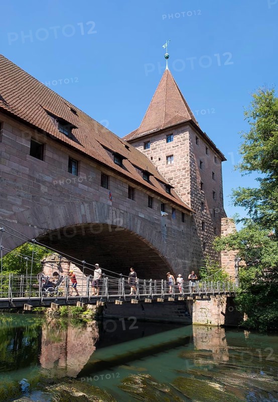 Kettensteg chain-hung bridge and Fronveste with Schlayerturm tower above river Pegnitz