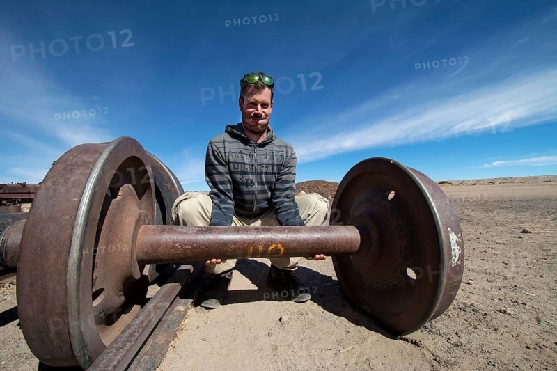 Young man lifting train axle like dumbbell