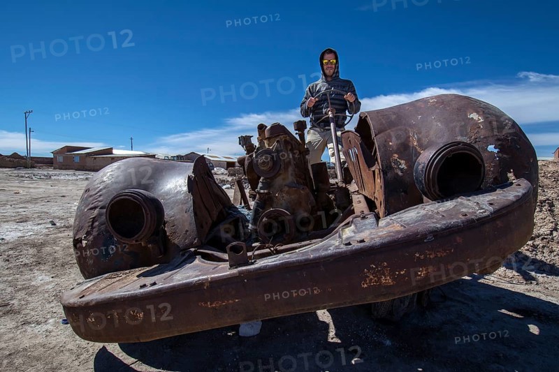 Young man sitting in rusty old car