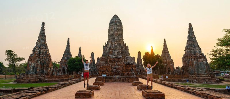 Two tourists jumping in front of a Buddhist temple