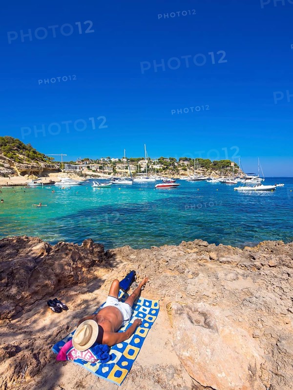Holidaymaker lying at the bay of Portas Vells