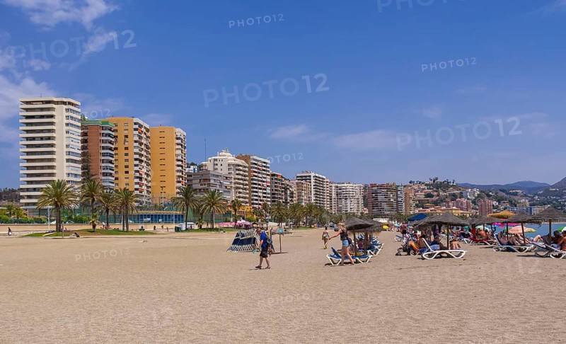 Deck chairs on the beach and skyscrapers behind at Playa de la Malagueta