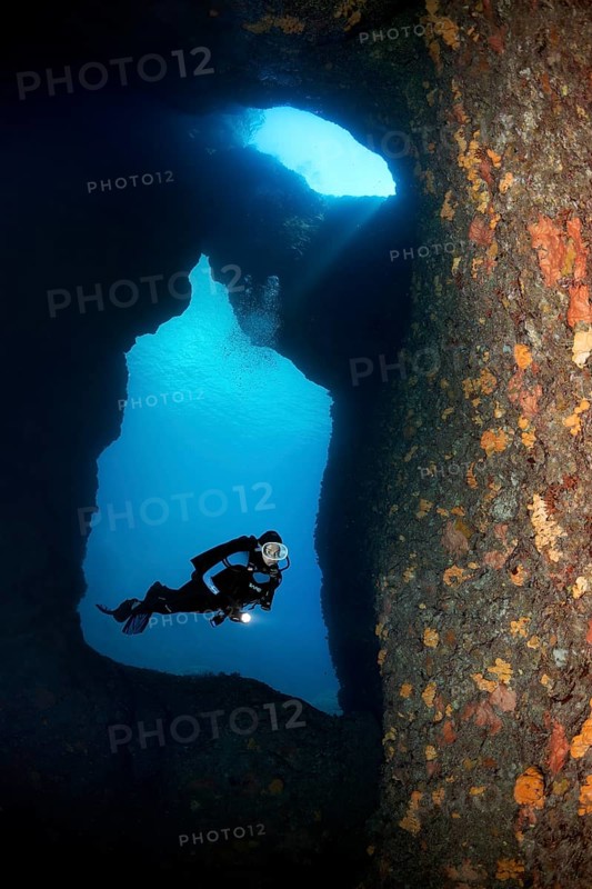 Diver with lamp in a rocky cave