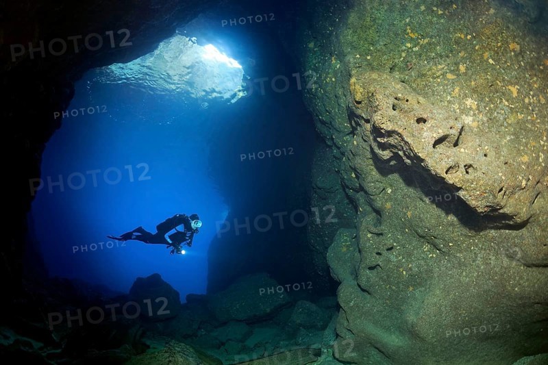 Diver with lamp in rocky cave
