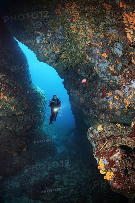 Diver with lamp in rocky cave