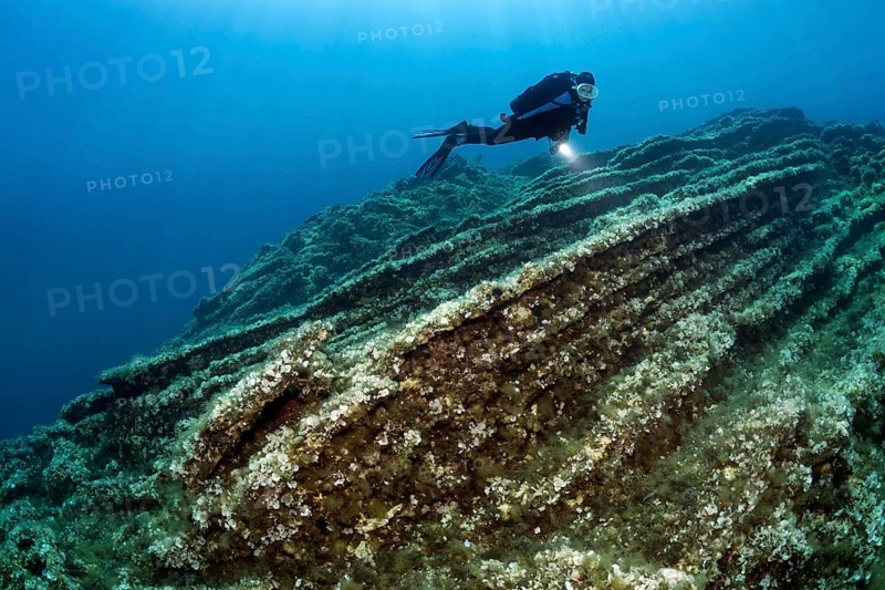 Diver observing layers of rock on shelf