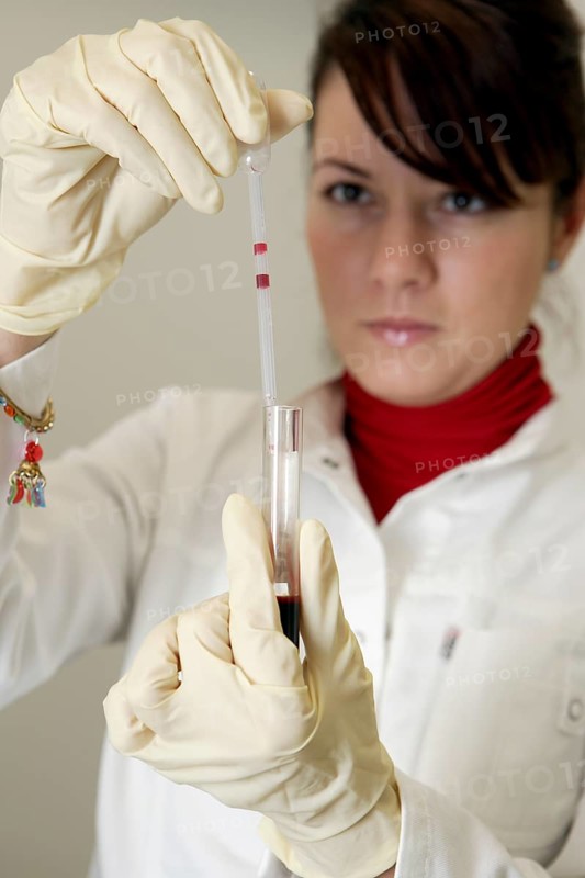 Female laboratory assistant in the laboratory holding a blood sample