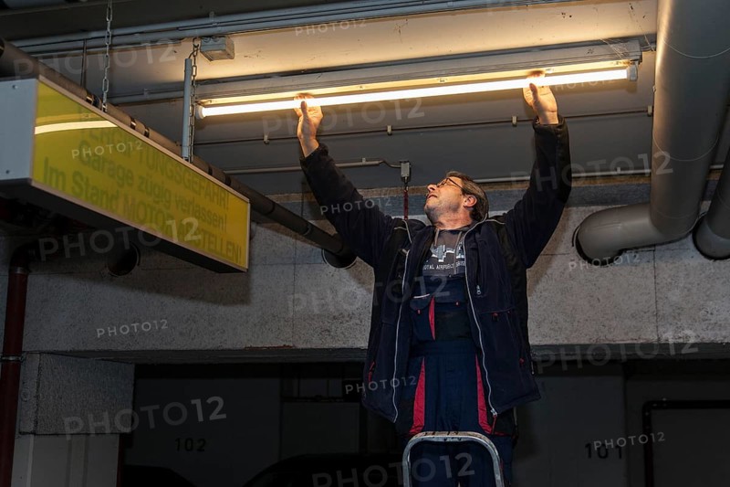 Caretaker replacing fluorescent lamp in underground garage