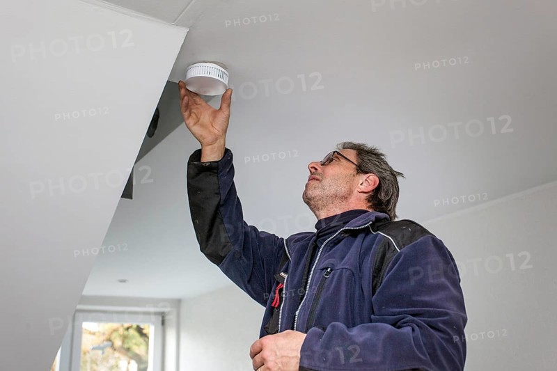 Caretaker with smoke detector in a stairwell
