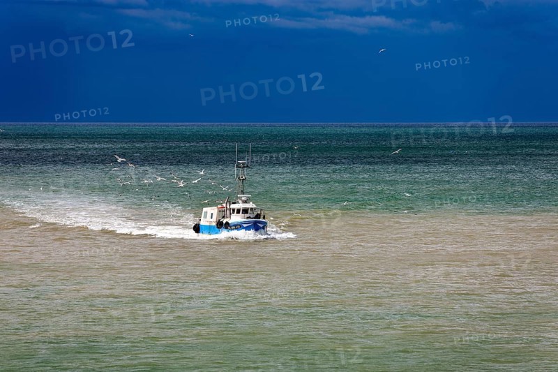 Fishing boat in the sea in front of storm front in Saint-Valery-en-Caux
