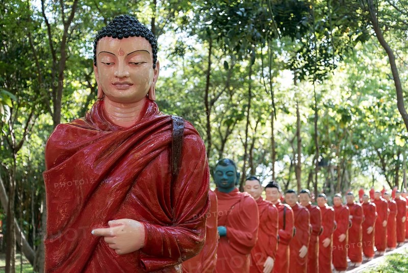 Statues of monks walking behind Buddha