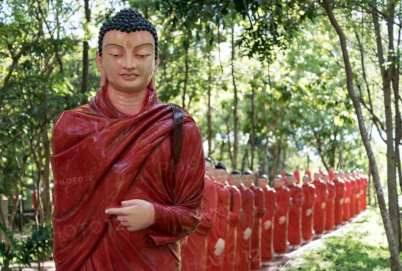 Statues of monks walking behind Buddha