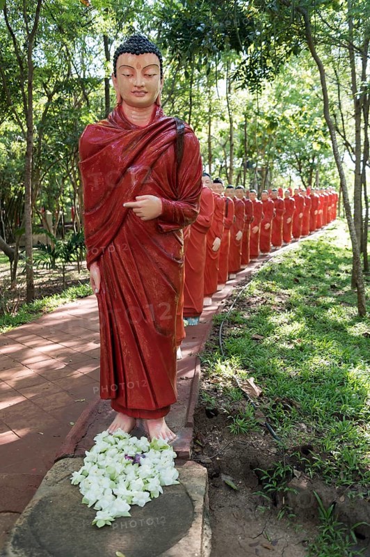 Statues of monks walking behind Buddha