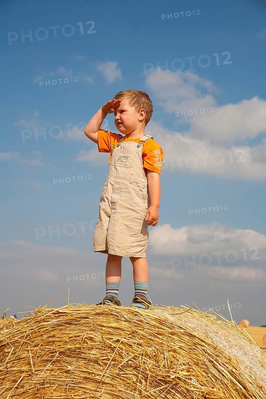 Little boy being on the lookut out on a straw bale