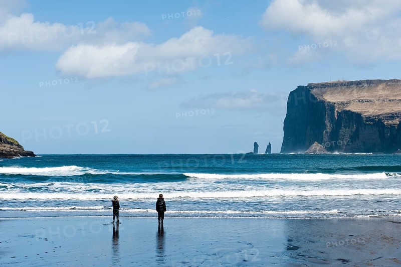 Two people on the black sand beach of Tjornuvik