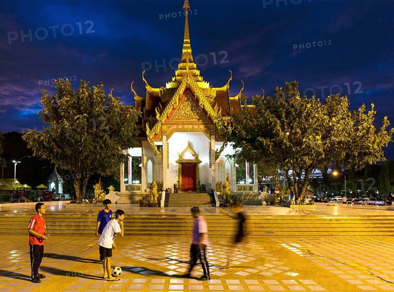 Teenagers playing football in front of the San Lak Muang