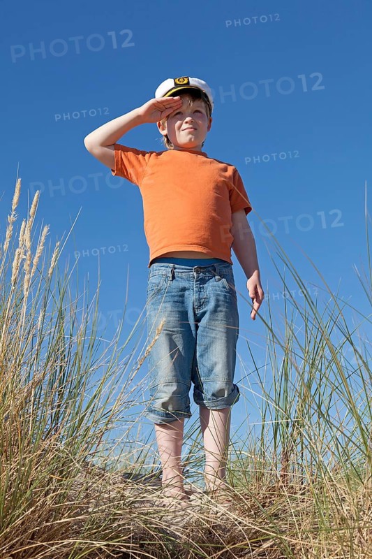 Boy wearing captain's hat on dunes