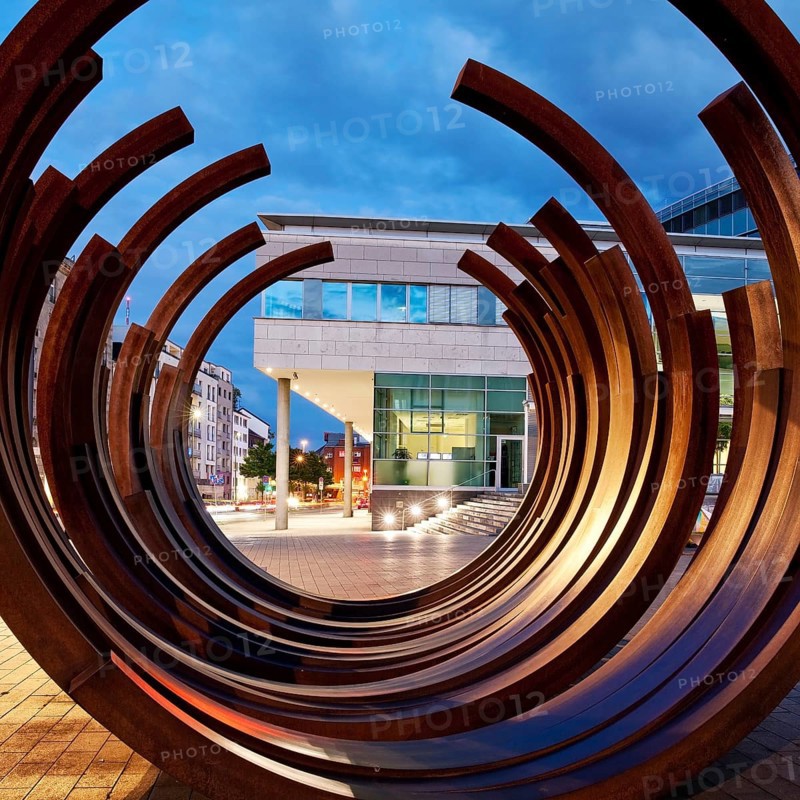 Modern sculpture of Bernar Venet with the inner city in the evening